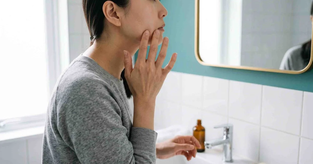 Mụn kê ở người lớn: các sẩn trắng nhỏ dưới bề mặt da vùng má soi trước gương phòng tắm