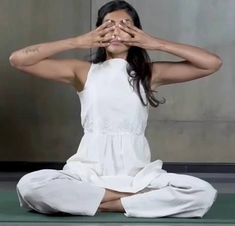 Người tập thực hiện thủ ấn Shanmukhi Mudra: dùng hai tay bịt tai và che mắt khi ngồi thiền để tập trung rung động của hơi thở Bhramari vào vùng xoang mặt.